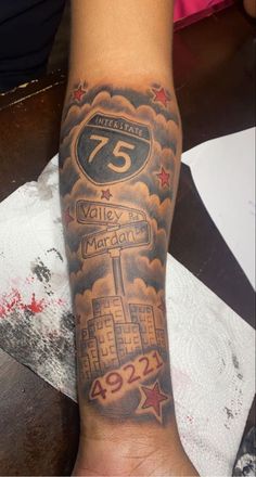 a person with a tattoo on their arm that reads 75 and has a street sign