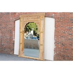 a mirror sitting on the side of a brick wall next to a doorway with an open door