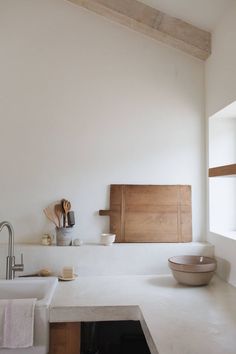 a white kitchen counter top with a sink and utensils on the shelf above it