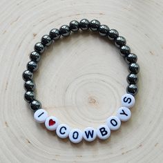 Plated Hematite beads and white plastic letter beads stating: I♡COWBOYS  Approximately 7 inches in length. This fun stretch bracelet is a great way to show off your love of all things country.  Makes a great gift for the cowboy lover. All bracelets are shipped in organza drawstring bags and boxed. >>S H I P P I N G details<< ✔️Ships in 1-2 days Country Beaded Bracelets, Country Bracelets Diy, Zach Bryan Bracelet Ideas, Western Bracelet Ideas, Country Clay Bead Bracelet Ideas, Beaded Letter Bracelets, Country Bracelets, Tyler Owens, Letter Bracelets