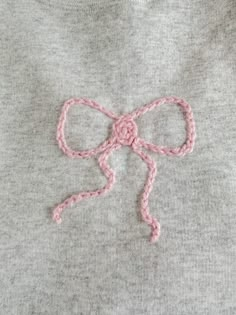 a close up of a sweater with a pink bow on the front and back of it