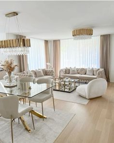 a living room filled with furniture and a chandelier above a glass top table