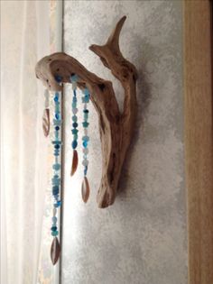 a piece of driftwood with beads hanging from it's side on the wall