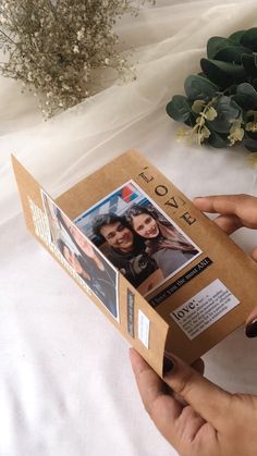 a person is holding up a box with photos on it and flowers in the background