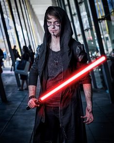 a man dressed as darth vader holding a light saber