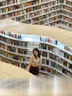 a woman standing in the middle of a library filled with lots of book shelves and bookshelves