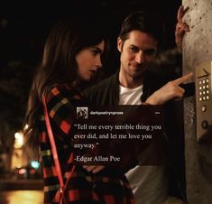 a man and woman standing next to each other near a wall with a quote on it