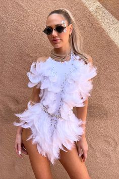 a woman in a white feather dress posing for the camera with sunglasses on her head