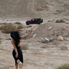 a woman flying a kite in the desert with a jeep on it's back