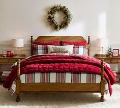 a bedroom decorated for christmas with plaid bedding and wreaths on the headboard