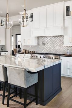 a large kitchen with white cabinets and marble counter tops, along with bar stools