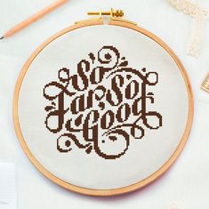 a cross stitch pattern with the words love and hope in brown on white fabric next to a pair of knitting needles