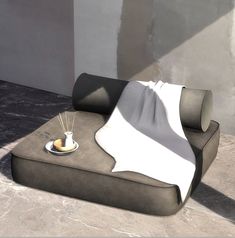 a couch with a white blanket on top of it next to a cup and saucer