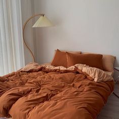 a bed with an orange comforter and pillows