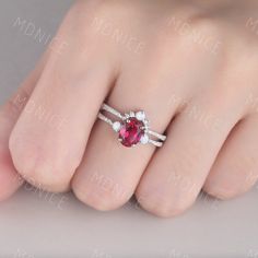 a woman's hand with a ring on top of her finger and an oval shaped ruby