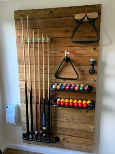 a wall mounted rack with pool balls and cues