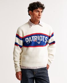 a man standing in front of a white wall wearing a sweater with the word detroit on it