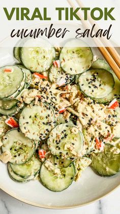 a white plate topped with cucumber salad and chopsticks next to it