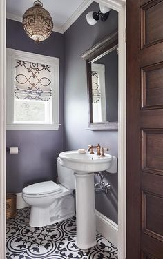 a white toilet sitting next to a sink in a bathroom under a mirror and light fixture