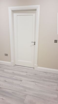 an empty room with a white door and wood floors