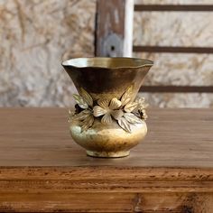 a gold vase sitting on top of a wooden table