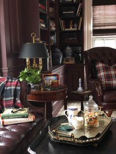 a living room with two leather chairs and a coffee table in front of a bookshelf