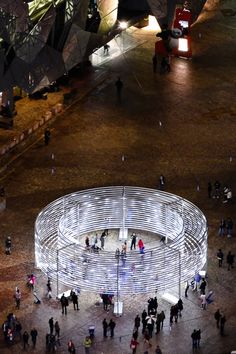 an aerial view of people standing in front of a circular structure with lights on it