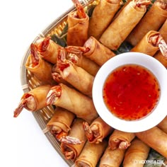 an overhead view of several spring rolls with ketchup in a bowl on the side