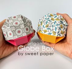 two hands holding origami globe boxes in different colors and patterns, with the words origami globe box by sweet paper