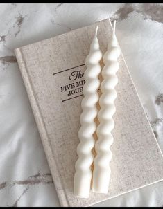 two white candles sitting on top of a book