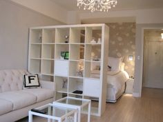 a living room filled with furniture and a chandelier hanging from the ceiling over a bed