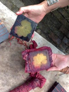 two hands holding small pieces of cloth with designs on them, and one person's foot in the air