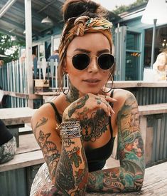 a woman with lots of tattoos on her arms and legs sitting on a wooden bench