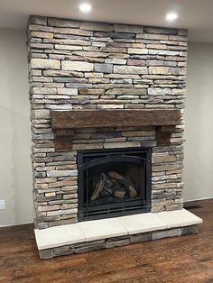 a stone fireplace in a living room with wood flooring