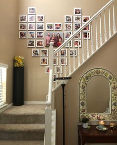 a staircase with pictures on the wall next to a mirror and table in front of it