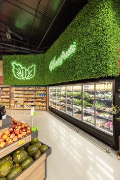 the produce section of a grocery store with artificial grass on the wall and shelves filled with fruits and vegetables