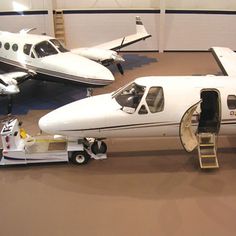 two small planes parked in a hanger with ladders attached to them and one plane on the ground