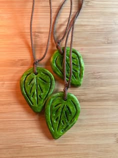 three green leaf shaped pendants on a wooden surface