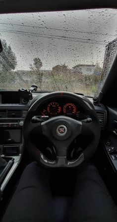 the interior of a car with rain on the windshield and steering wheel, dashboard lights, dash board