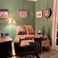 a living room with green walls and pictures on the wall above the reclining chair