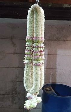 white flowers hanging from the ceiling next to a blue barrel