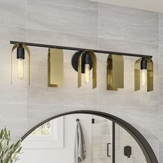 three lights are hanging on the wall above a mirror in a bathroom with marble walls