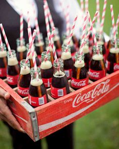 a tray full of coca - cola bottles with straws in them