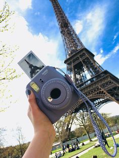 a person holding up a camera in front of the eiffel tower