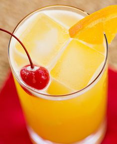 an orange drink with ice and cherries on the rim, garnished with a cherry