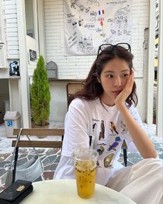 a woman sitting at a table with a drink in front of her