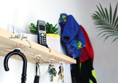 a wooden shelf with keys, umbrella and cell phone hanging on the wall next to it