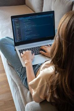 a woman sitting on a couch using a laptop computer