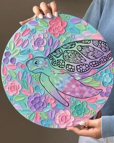 a woman holding up a colorful paper plate with a turtle on it's side