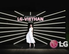 a woman is standing in front of a large sign that says lg - viethan